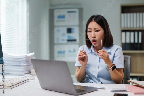Cuadro en lienzo Asian businesswoman in office holding glasses, shocked and stressed as she reads
