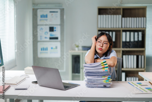 Photos Young businesswoman feeling stressed and exhausted from a large stack of paperwo