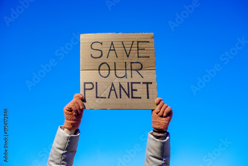 Tableau sur toile Activist holding cardboard save our planet sign under a clear blue sky