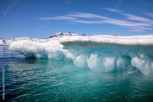 Glacial blue iceberg and sky background. Underside of a snow covered iceberg glistening in sunlight, in Svalbard, a Norwegian archipelago between mainland Norway and the North Pole