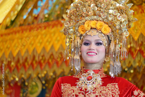 Close-up of a beautiful Acehnese bride wearing a majestic golden headdress and intricate red traditional wedding attire, smiling radiantly