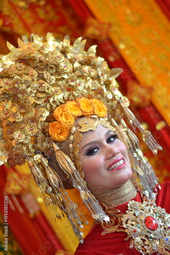 Close-up of a beautiful Acehnese bride wearing a majestic golden headdress and intricate red traditional wedding attire, smiling radiantly