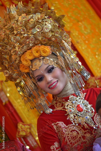 Close-up of a beautiful Acehnese bride wearing a majestic golden headdress and intricate red traditional wedding attire, smiling radiantly