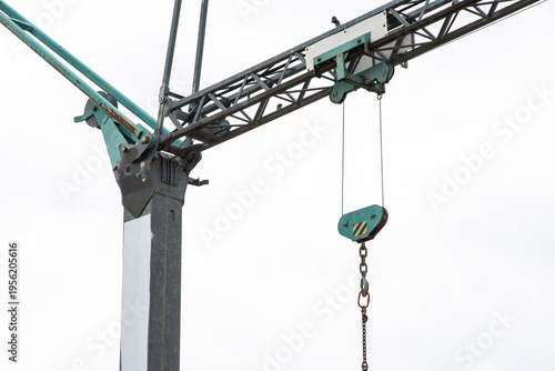 Tower crane lifting construction materials on building site against blue sky, urban development concept