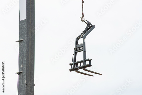 Tower crane lifting construction materials on building site against blue sky, urban development concept