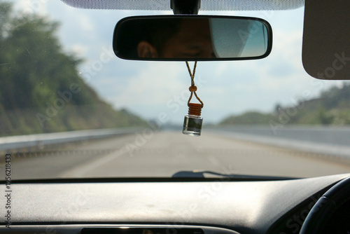 Canvastavla Car interior view with hanging air freshener and rearview mirror on highway, dri