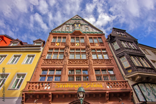 Ornate Freiburg facade of former newspaper building with sculptures timber framing and decorative sandstone details under dramatic sky