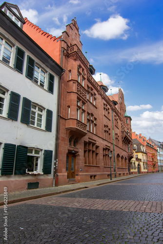 Ornate historic building in Freiburg im Breisgau with red stone facade decorative windows balconies and detailed architectural elements along a quiet city street