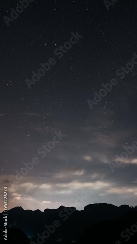 An expansive and majestic night sky adorned with countless stars illuminates the serene silhouette of a mountain range.