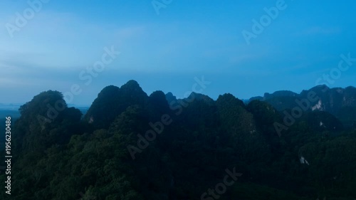 A breathtaking aerial view captures the essence of a majestic mountain landscape, where rugged peaks meet a serene blue sky, a harmonious symphony of nature's artistry.