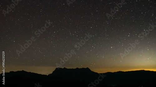 A mesmerizing panorama of the night sky, capturing the celestial beauty and the sense of awe as the stars glitter above a mountain silhouette. 