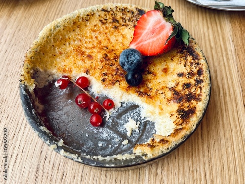 Close-up of creamy crème brûlée with burnt sugar crust and fresh berries, elegant dessert presentation, top view composition.