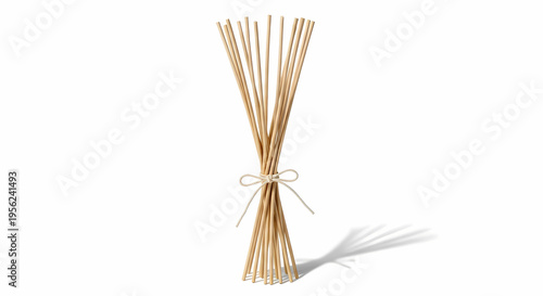 A bundle of natural wooden diffuser reeds tied with a string, casting a shadow on a white background.