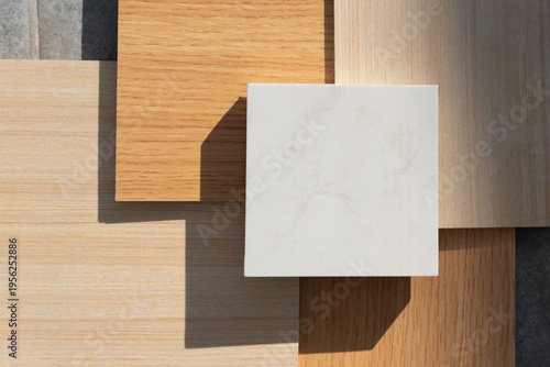 An aesthetic arrangement of interior design material samples featuring light and warm wood grain textures paired with a central white marble or quartz stone swatch.