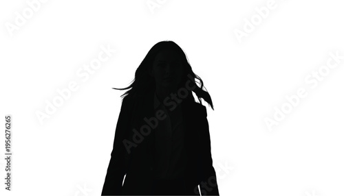 Silhouette of a woman with flowing hair walks forward wearing a dark jacket against white.