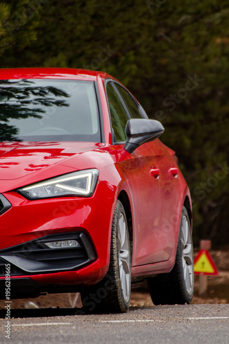 Foto Close-up of a modern red hatchback car on a forest road with LED headlights