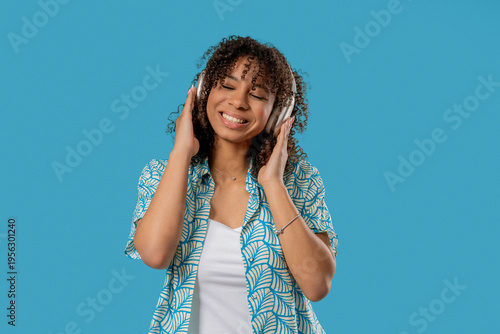 African Pretty Woman Listening Music, Dances With Wireless Headphones On Blue