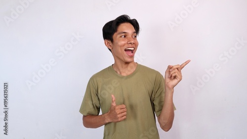 excited young asian man gesturing okay, pointing and looking to the side
