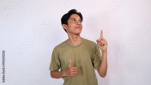 young asian man smiling ok gesture, pointing and looking up