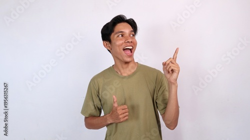 young asian man smiling ok gesture, pointing and looking up on