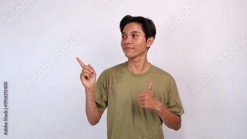 young asian man smiling ok gesture, pointing and looking to the side