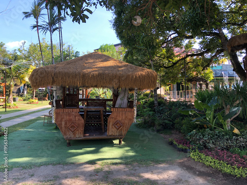 bamboo hut with a grass roof located in a park.