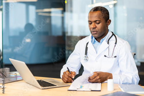 Canvas Print Mature medical professional sitting at a desk, reviewing patient charts and maki