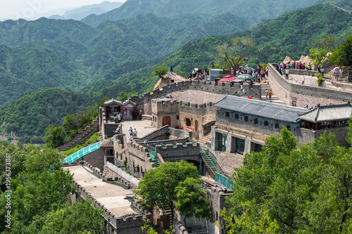 A scenic view of the winding Great Wall of China at Badaling, crowded with tourists climbing the fortifications along the lush green mountain ridges.