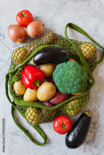 Fresh garden produce in a green mesh bag sits on a kitchen counter, ready for healthy cooking
