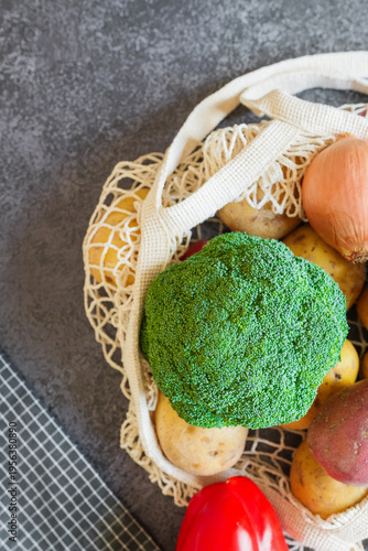 Foto Freshly harvested vegetables placed in a reusable mesh grocery bag on a dark kit