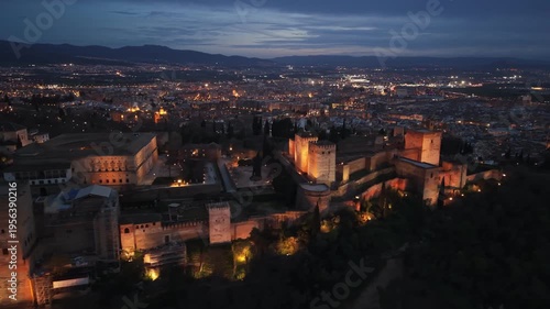 Illuminated walls and towers of the Alhambra palace in Granada, Spain. Night aerial view of the illuminated Alhambra fortress in Granada