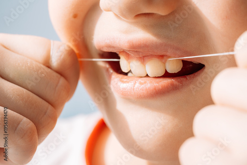 Photos Close up child flossing teeth with dental floss string, oral hygiene and prevention concept