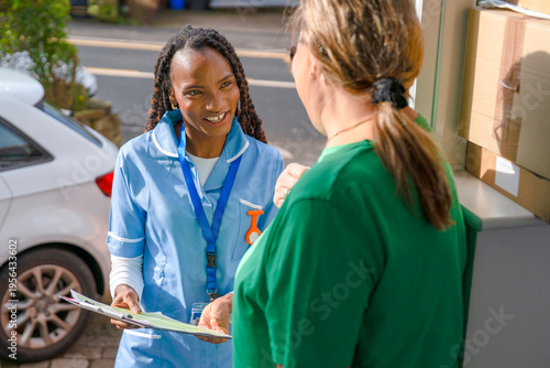Healthcare worker talks to patient at home in a neighborhood during the day