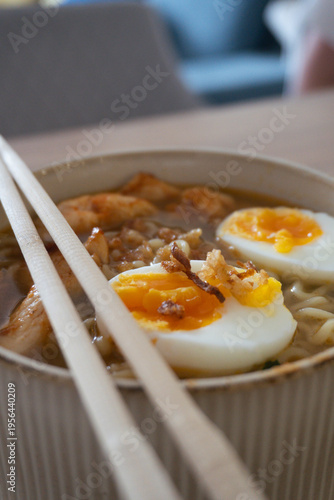 Delicious bowl of ramen with soft-boiled eggs and chicken, ready to be enjoyed with chopsticks