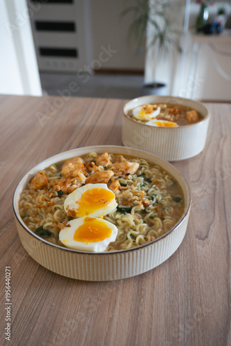 Delicious ramen noodles with chicken and soft-boiled eggs served in bowls on a wooden table