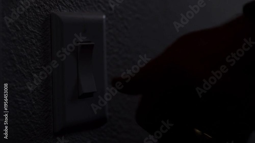 Close up of a human hand switching off a light toggle in a dark room