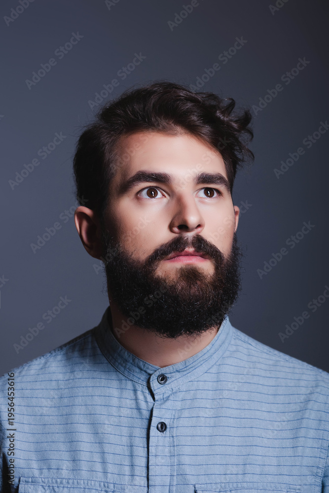 Obraz premium Portrait of a thoughtful young bearded man looking away from the camera.