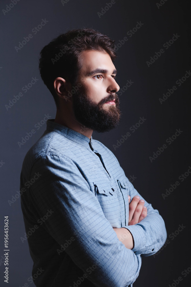 Fototapeta premium Side profile portrait of a handsome bearded man in a blue shirt.