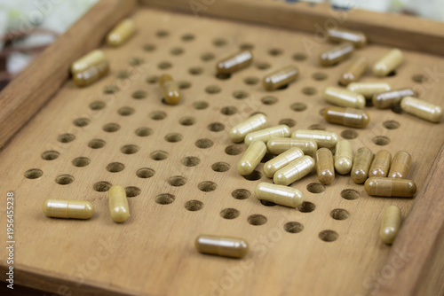 cose up herbal capsules on wooden tray for manual filling process, traditional medicine preparation, supplement and healthcare concept.