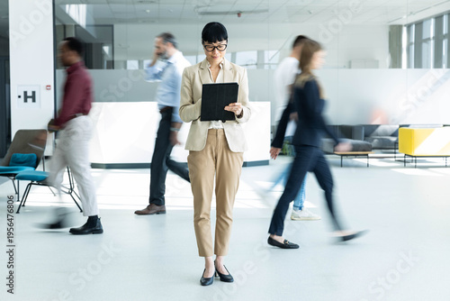 Cuadro en lienzo Businesswoman standing still and focusing on digital tablet, ignoring motion blu