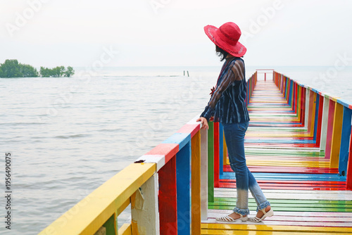 Woman in Red Hat Looking at the Sea from Colorful Wooden Boardwalk