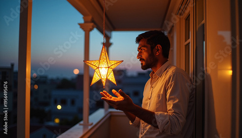 Man holding illuminated star decoration on balcony at dusk. Star is glowing warmly, creating a cheerful atmosphere in evening light. Concept of celebration and joy with star ornament.