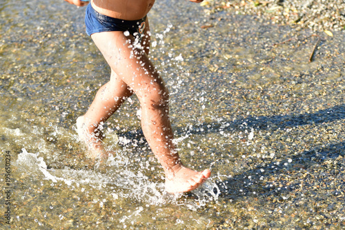 Kind an einem See, hat Spaß und springt durchs Wasser und spritzt