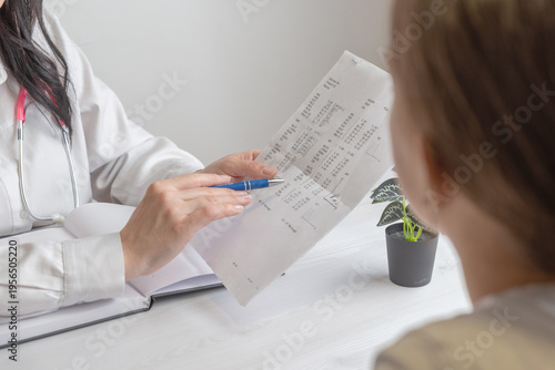 doctor showing medical report to patient over shoulder view representing diagnostics, healthcare data and clinical evaluation