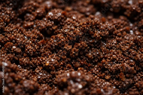 Close up view capturing macro detail of wet dark brown coffee grounds, portraying rich texture and tiny moisture droplets suitable for a conceptual background