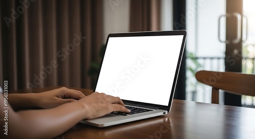 Person typing on a laptop with a blank screen