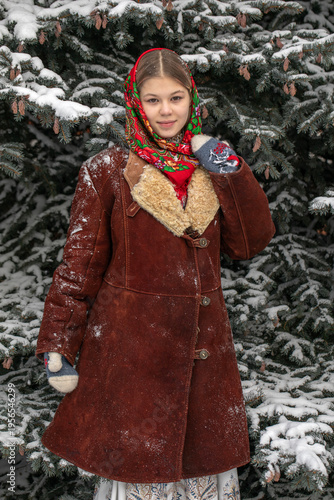 Winter portrait of a young beautiful village girl in a headscarf