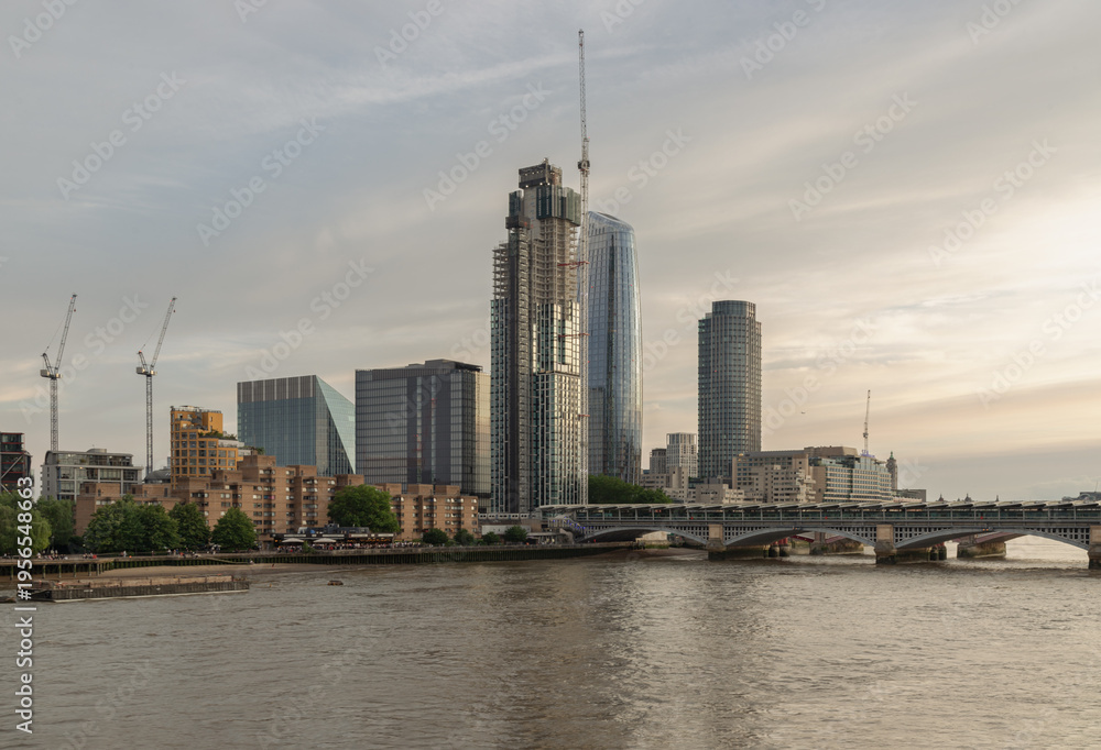 Obraz premium As the evening light softens into a hazy gold, the Blackfriars skyline reveals a city in a constant state of rebirth. The slender, curved silhouette of One Blackfriars often called 'The Vase' glimmers