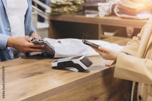 Foto Customer making contactless payment with smartphone at clothing store checkout t