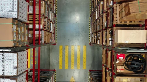 Top down drone moving backward over warehouse aisle